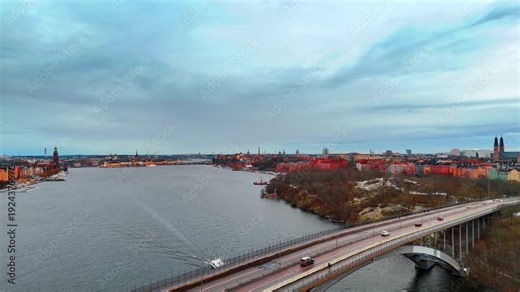 Flyover the bridge and moving over the grey waterscape in the city. Cloudy day in Stockholm, Sweden from drone.