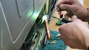 Fixing the refrigerator that not cooling enough by recharging Freon tube. Master attaches a tube with freon with a soldering iron