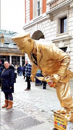 How gold man statue seating on nothing works to entertain his audience on the street of London.#art