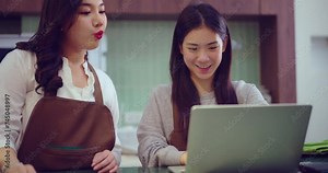 Beautiful young Asian woman working at the bar counter at a coffee shop or restaurant. Together they use computers to promote their own businesses.