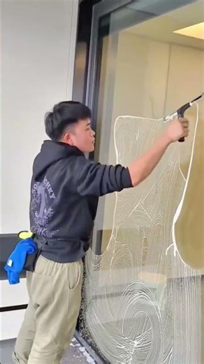 A professional window cleaner using a squeegee to clean a glass door
