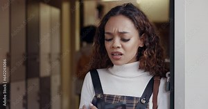 Bullying, message and phone of a student at college reading bad news or serious online chat in hallway. Annoyed girl at university with smartphone for school notification, gossip or cruel post