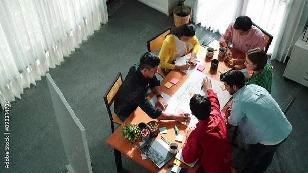 Top down view of diverse people brainstorming and making scrum task board. Group of skilled business team working together and writing sticky notes to share plan and using kanban board. Convocation.