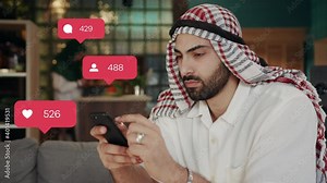 Handsome mixed-race arabian bearded man wearing traditional Muslim clothes using smartphone in his modern house. User interface. Likes and comments.