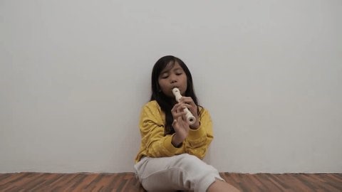 Cute little Asian girl playing recorder flute, musical instrument