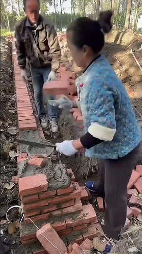 Female bricklayer laying red brick wall with concrete