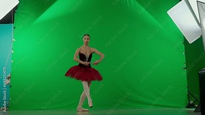 Portrait of female on chroma key green screen background. Full body shot ballerina in red tutu and dark body dancing posing in studio.