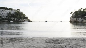 Sand beach with cliffs and vessel on the background at sunset called Cala Galdana located in Menorca, an island of Spain.
