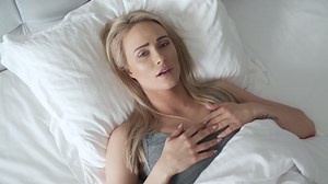 Premium stock video - Women sitting on bed holding her head  she has a painful headache