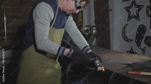 Blacksmith cuts iron details via plasma cutter at his workshop, slow motion.