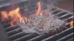 Cooking hamburger. Beef or pork cutlet grilling on grid. Cook man preparing a burger patty on the grill. Laid on the grill and overturned flatware. Family summer vacation. Slow motion.