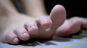 Close-up Tired Child Wiggles his Toes while Lying on the Bed in Room. 4K
