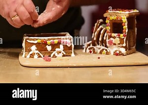 Detailed close-up video of a gingerbread train being decorated with white icing and colorful sweets, capturing the cozy atmosphere of traditional Christmas baking prepared by caring grandparents