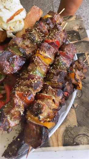 LAMB SOUVLAKI - INGREDIENTS :- 2 kg lamb leg or shoulder, cut into approximately 25g square pieces- 2 yellow peppers- 2 red peppers- 2 green peppers- 1 large onion- 3 tomatoes- Salt, pepper, and oregano- Olive oil and lemon juice- 60 ml lemon juice- 40 ml olive oil- 3 cloves of garlic- 30 ml water- 4 sprigs of thyme- Salt and pepper METHOD - :1. Cut the vegetables into squares similar in size to the meat.2. Skewer the meat and vegetables on a wooden stick that has been soaked in water to prevent