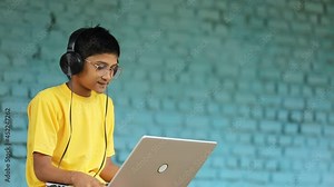 Indian child using laptop and headphone. attending online classes