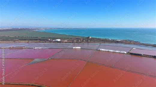 Salt flats and ocean meet under blue sky. Salt flats extend across land next to the ocean under a blue sky.