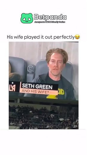 Sarcasm wrrld on Instagram: "The video captures a humorous moment at a soccer stadium involving actor Seth Green and his wife, Clare Grant. The scene begins with the couple sitting in the stands at BMO Stadium during an LAFC game, looking up toward the Jumbotron as the camera pans across the crowd. As the stadium screen displays their live image with the caption “Seth Green and his wife?” Seth maintains a perfectly deadpan, almost intense expression, staring directly into the lens. In a stark an
