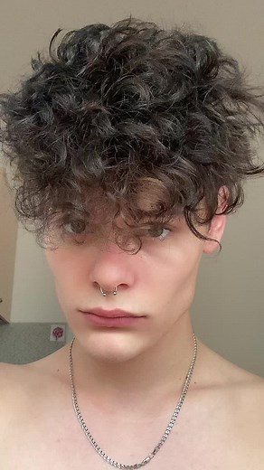 Curly-Haired Individual Flexing Muscles in Kitchen