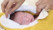 Cute asian newborn baby girl lying down on her bed and looking her...