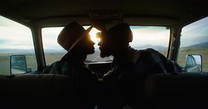 Young Couple Kissing in Car During Road Trip at Sunset