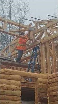 Log Home Build - The laminated support beam is fitted in place and adjusted at the peak of the roof