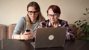 Granddaughter tells her old grandmother how to use a laptop.