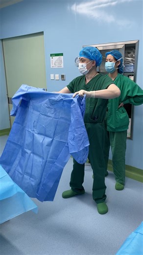 Nurse Assists Doctor with Surgical Gown Preparation