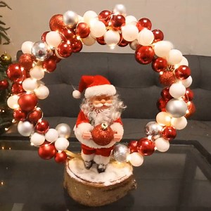 Santa standing under a Christmas ornament arch | Life and Fun Story