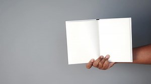 Holding an empty notebook against a plain gray background