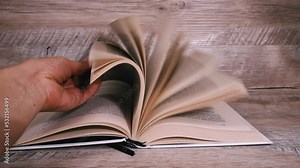 Turning pages in a white book close up slow mo. Reading a book, intelligence. Pages flow one after another. Women's hands leaf through a book.