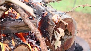 Gooey marshmallow almost burning drips in slow motion by the rising flames and smoke to add black char