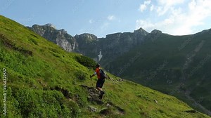 A hiker walks on mountain trail at high altitude in a beautiful day