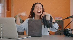Vlogger or content creator is filming an unboxing video in her home studio. Young female influencer is holding a box and talking to camera explaining and smiling. Excited to open and see gadget inside