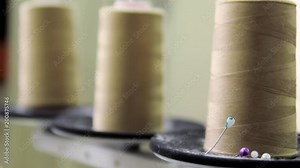 Pink plastic spools of high quality cotton sewing thread, close-up. All-purpose thread spools on a sewing machine spindle.