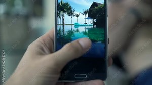 Close up of male hand browsing photos on smartphone sitting in garden