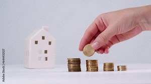Crop anonymous female collecting coins in pile for real estate investment and saving money for buying a house. Mortgage loan concept
