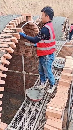Arranging bricks to create a curved archway structure using mortar and tools on scaffolds