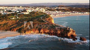 Nazare Portugal Lighthouse in Praia do Norte during sunset golden hour, Aerial dolly out