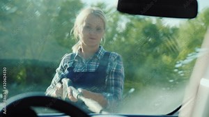 Inside view of a car, a woman washes her car with a high pressure washer