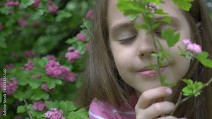 Girl smelling a branch of a cherry blossom tree in a park in spring time.