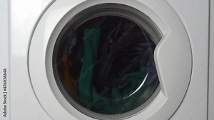 Close-up of a washing machine washing colored clothes. Cylinders. A conceptual washing machine for laundry, Industrial laundry or home washing. wash or spin mode. slow motion,