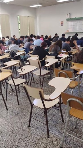 Examen parcial con banco para sentarse y banco para poner la mochila. Con pasillos para caminar.