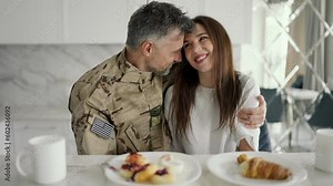 The soldier has breakfast and chats with his girlfriend. Warm hugs and cheerful family breakfast atmosphere