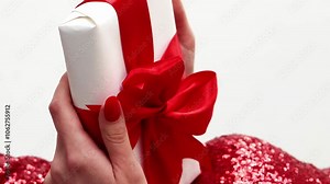 Vertical video. Xmas gift. Holiday surprise. Elegant unrecognizable woman in sparkling dress holding present box wrapped with red ribbon isolated on white.