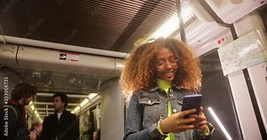 Young black woman using smartphone while travelling on train