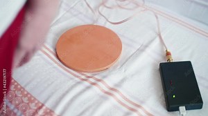Woman puts special coil on bed and sits down on it starting her treatment. Alternative medecine