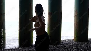 female silhouette against the background of dark pillars. a woman is dancing. the average plan. the camera is moving