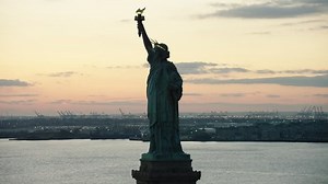 Aerial view of orbiting the Statue of Liberty to downtown Manhattan close to night. Wide shot. 4k shot with a RED camera.