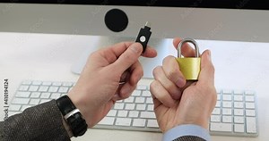 The man fastens a metal lock, which he holds in his hand, and brings a USB flash drive to the lock - an electronic key, close-up. Modern systems for encrypting access passwords.