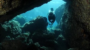 cave diving lady underwater scuba divers exploring caves and having fun ocean scenery sun beams and rays background